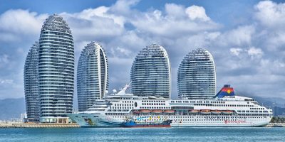 都柏林湾弧形海岸线从达尔基岛上空向北望去，远处都柏林城市轮廓隐约可见，蓝天白云倒映水面